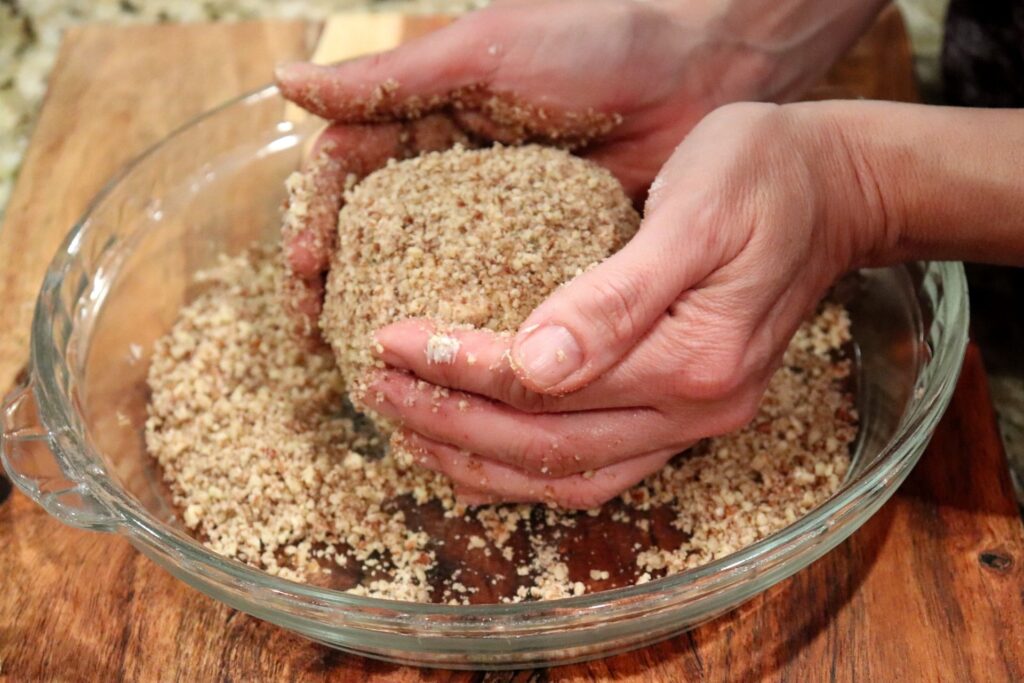 Roll the cheese ball into the chopped pecans before putting on the serving platter.