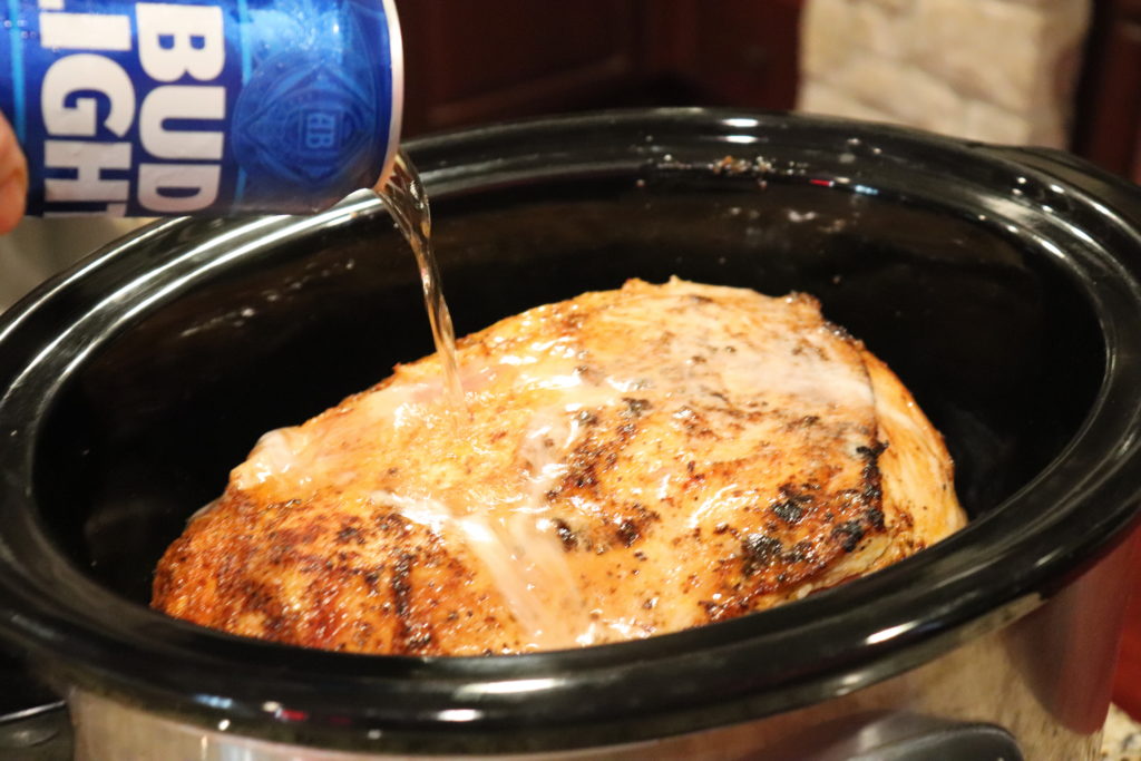 A pork butt that has been seared on all sides and put in the slower cooker with beer added to simmer in.