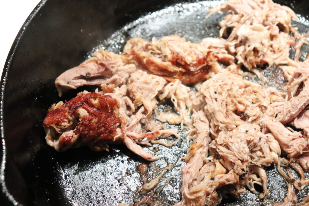 Slow cooked pork butt is put in a cast iron to crisp up the edges for bite full of texture. 