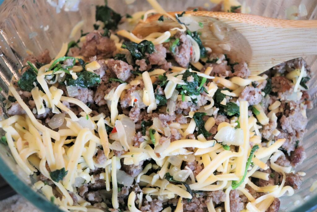 Pictured, our Calzones filling is Italian sausage filled, highlighted with caramelized onion, baby spinach, and smoked gouda cheese!   