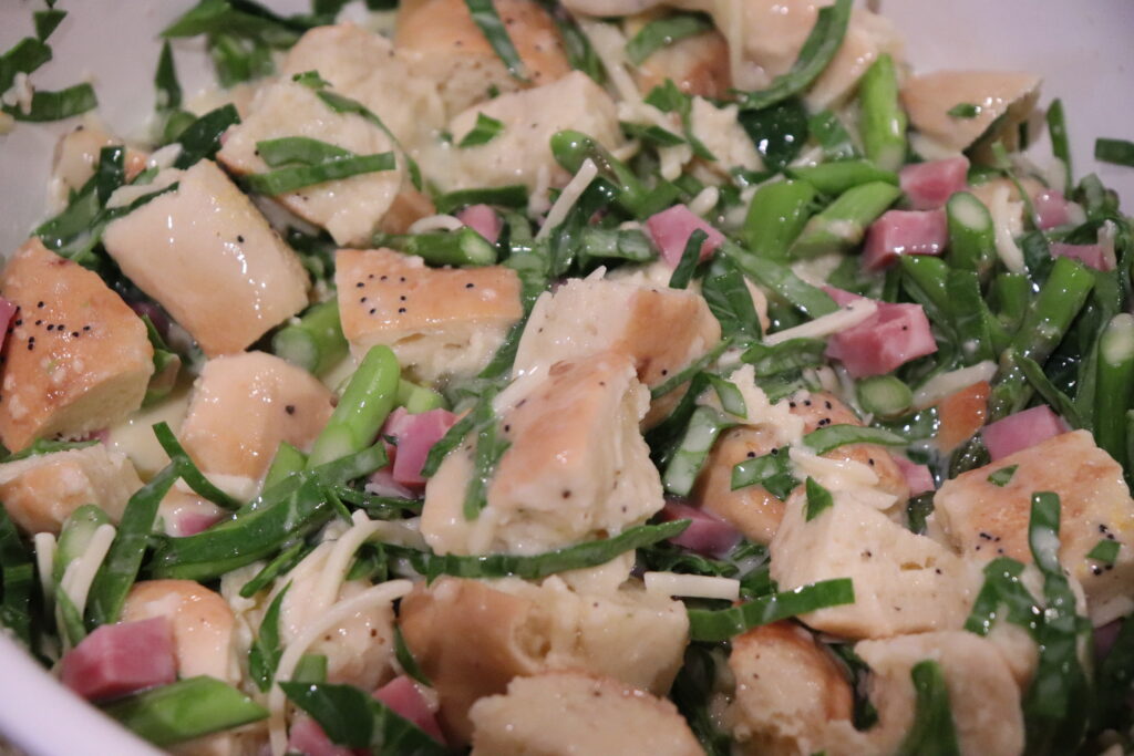 The Bagel Strata With Asparagus And Ham Ingredients mixed together close up to see all fo the texture and colors.