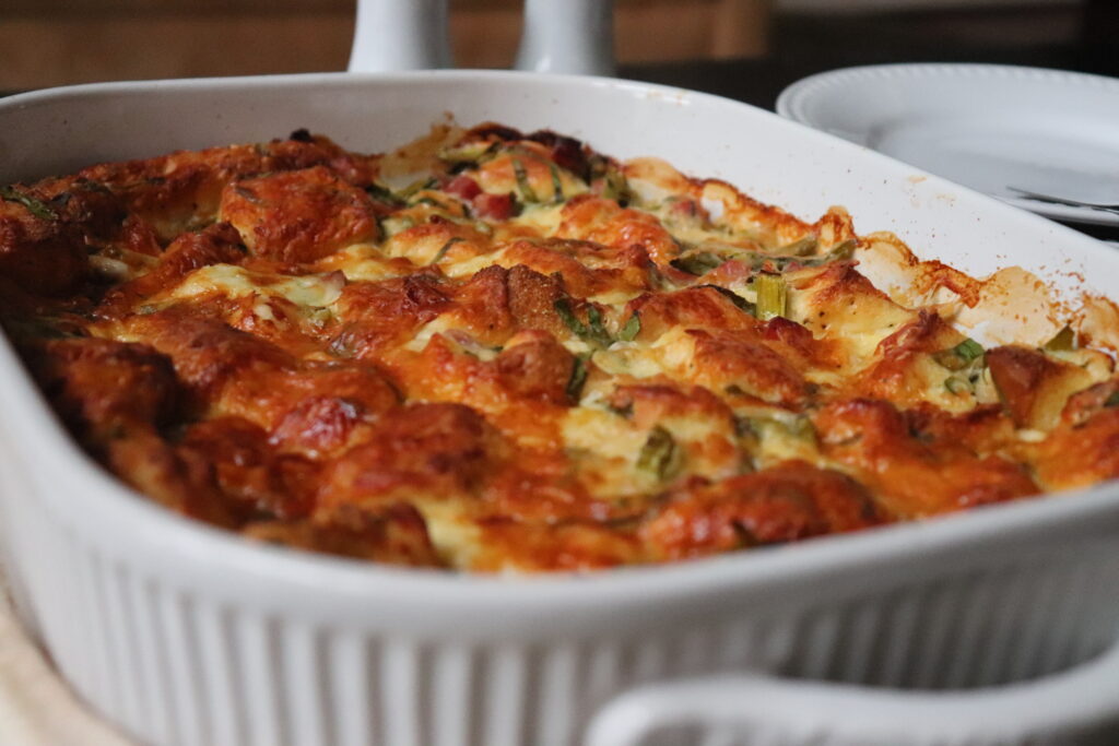 Fresh out of the oven the beautiful golden brown Bagel Strata With Asparagus And Ham is served.